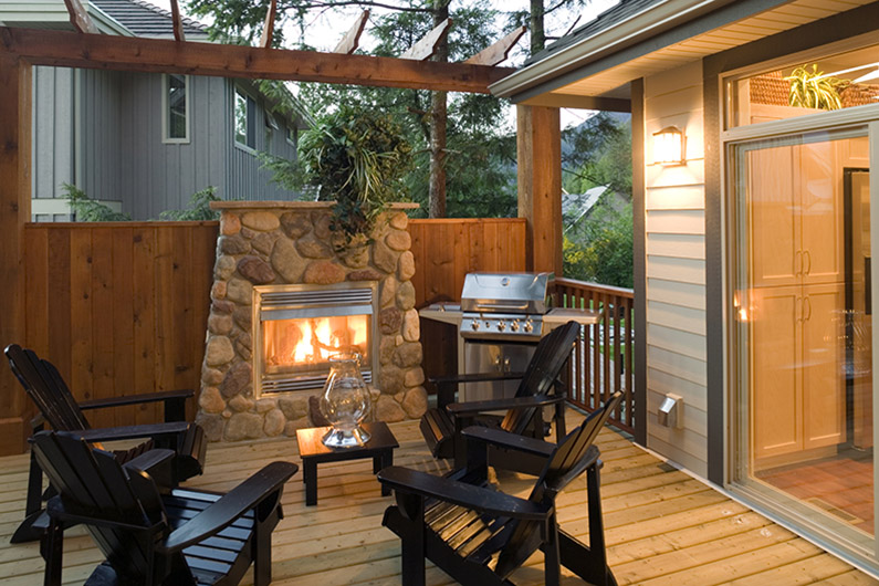 Outdoor patio with fireplace, chairs and barbeque grill